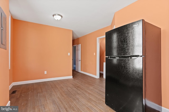 kitchen with visible vents, wood finished floors, baseboards, and freestanding refrigerator