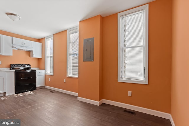 kitchen featuring electric panel, under cabinet range hood, white cabinetry, black / electric stove, and baseboards