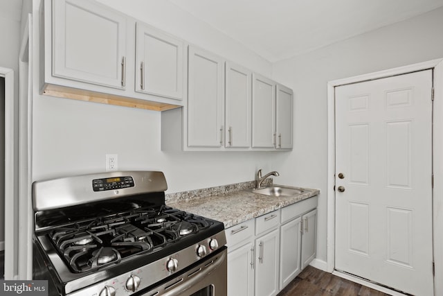 kitchen featuring white cabinetry, dark wood-style flooring, stainless steel gas range, and a sink