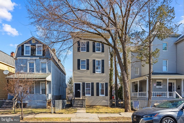 view of front of house featuring a fenced front yard, a gambrel roof, and covered porch