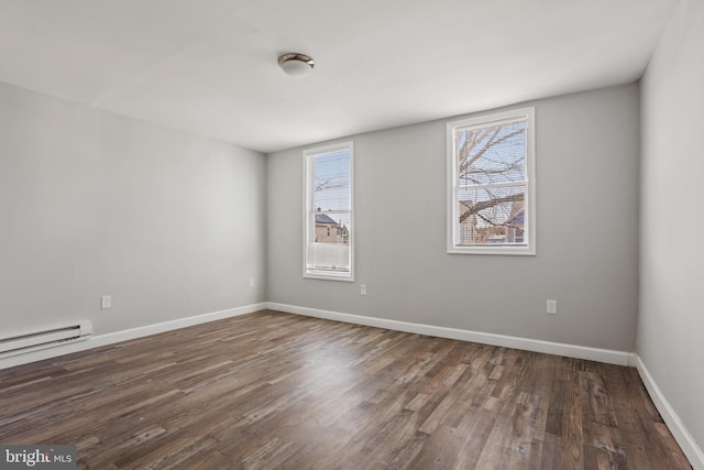 spare room featuring baseboard heating, baseboards, and wood finished floors