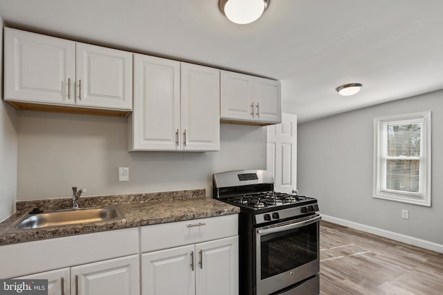 kitchen featuring white cabinetry, stainless steel gas range, and a sink