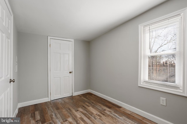 unfurnished bedroom featuring a closet, baseboards, and dark wood-style floors