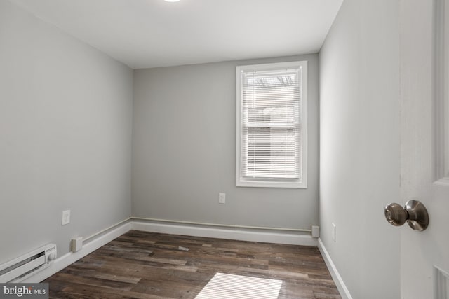 spare room featuring baseboard heating, dark wood-type flooring, and baseboards