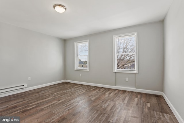 empty room with a baseboard radiator, baseboards, and wood finished floors