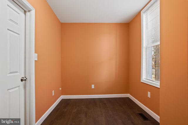 spare room with visible vents, baseboards, and dark wood-style flooring