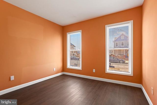 empty room with baseboards, plenty of natural light, and dark wood-type flooring