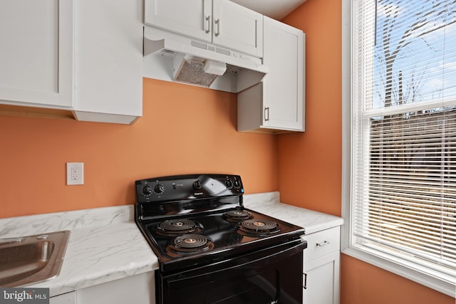 kitchen with under cabinet range hood, a healthy amount of sunlight, white cabinets, and black range with electric stovetop