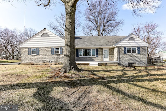 view of front of house with stone siding, a front yard, and roof with shingles