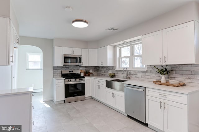 kitchen featuring visible vents, backsplash, light countertops, stainless steel appliances, and a sink