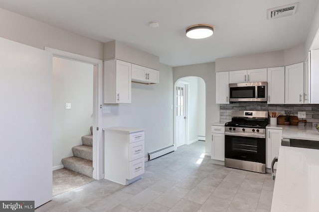 kitchen featuring visible vents, light countertops, appliances with stainless steel finishes, arched walkways, and a baseboard radiator