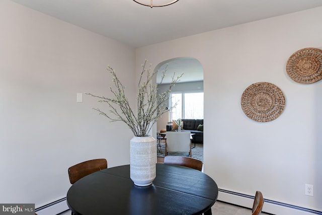 dining area with arched walkways and a baseboard heating unit