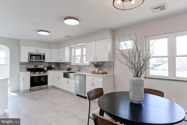 kitchen featuring tasteful backsplash, visible vents, light countertops, appliances with stainless steel finishes, and a sink