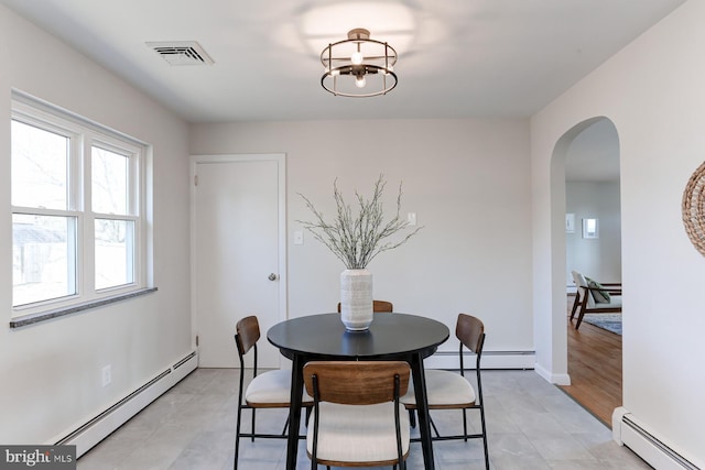 dining room featuring arched walkways, visible vents, a baseboard heating unit, and an inviting chandelier