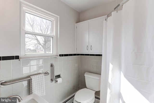 bathroom with a baseboard radiator, toilet, and tile walls