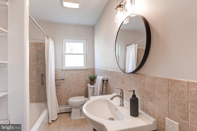 bathroom with tile patterned flooring, a baseboard heating unit, toilet, tile walls, and a sink