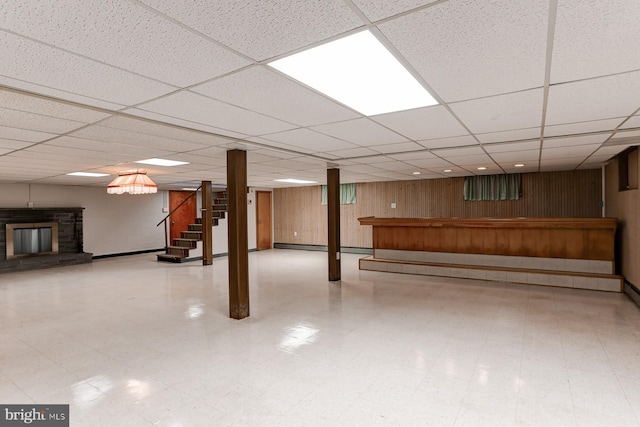 finished below grade area with stairs, tile patterned floors, a fireplace, and wood walls