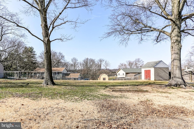 view of yard with a storage shed, an outdoor structure, and fence