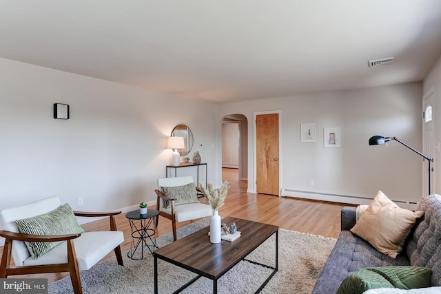 living room with visible vents, a baseboard radiator, light wood-style flooring, arched walkways, and baseboard heating