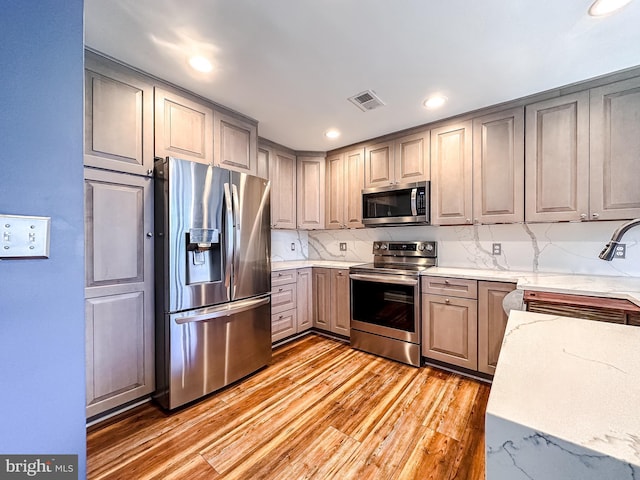 kitchen featuring visible vents, light stone counters, light wood-style flooring, gray cabinets, and stainless steel appliances