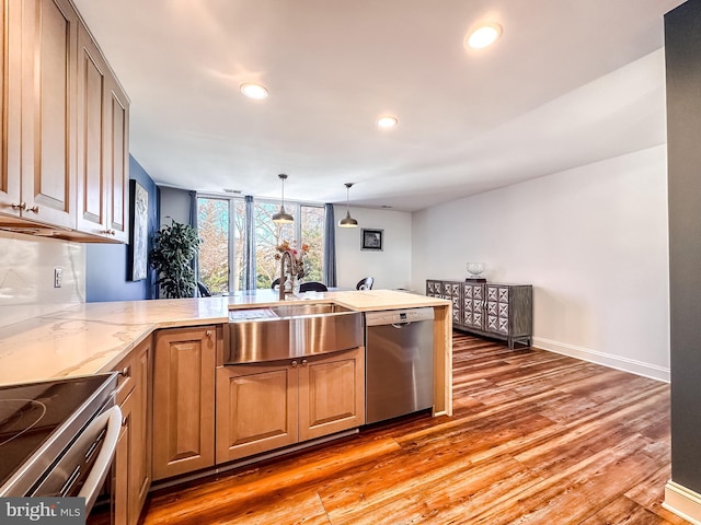 kitchen featuring light wood finished floors, light stone countertops, recessed lighting, appliances with stainless steel finishes, and a peninsula