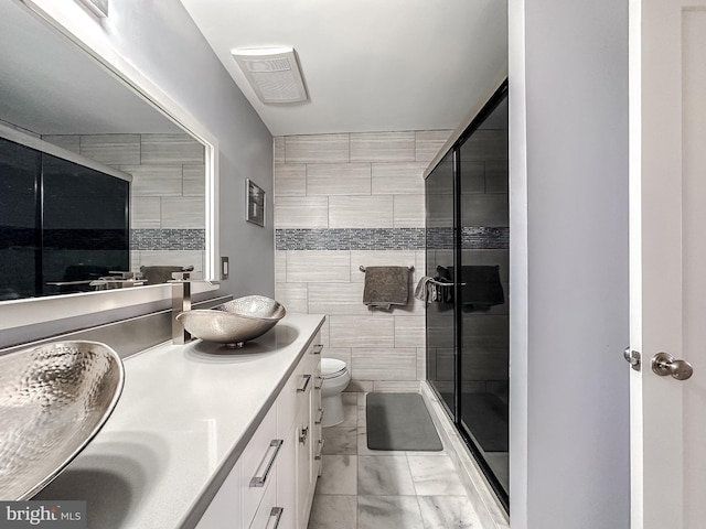 bathroom featuring tile walls, toilet, a stall shower, and a sink