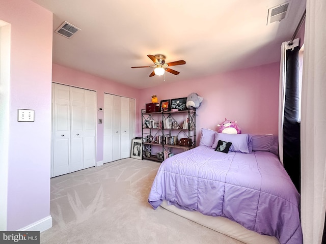 bedroom featuring visible vents, carpet floors, two closets, and baseboards