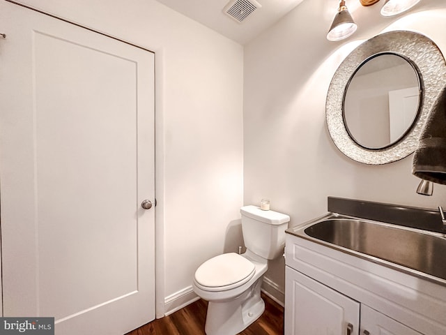 bathroom with visible vents, baseboards, toilet, wood finished floors, and vanity