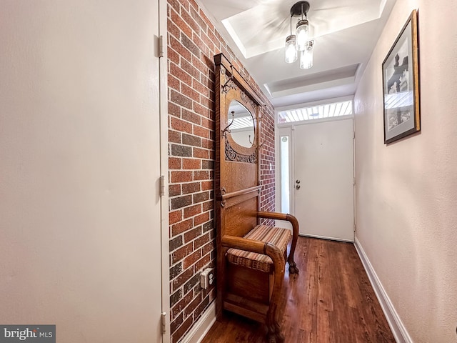 interior space with brick wall, baseboards, and wood finished floors