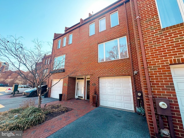 townhome / multi-family property with brick siding, driveway, and an attached garage