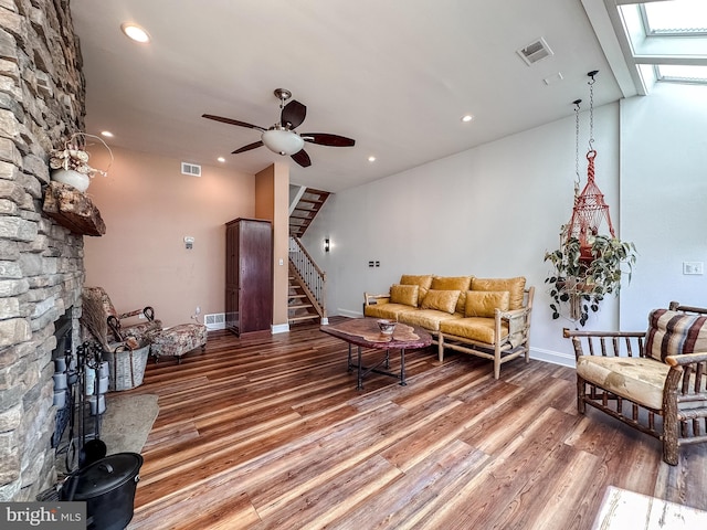 living room with visible vents, ceiling fan, stairs, and light wood-style floors