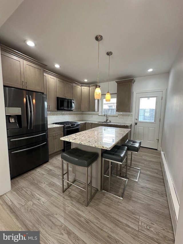 kitchen with backsplash, range with gas stovetop, a kitchen breakfast bar, black refrigerator with ice dispenser, and a sink