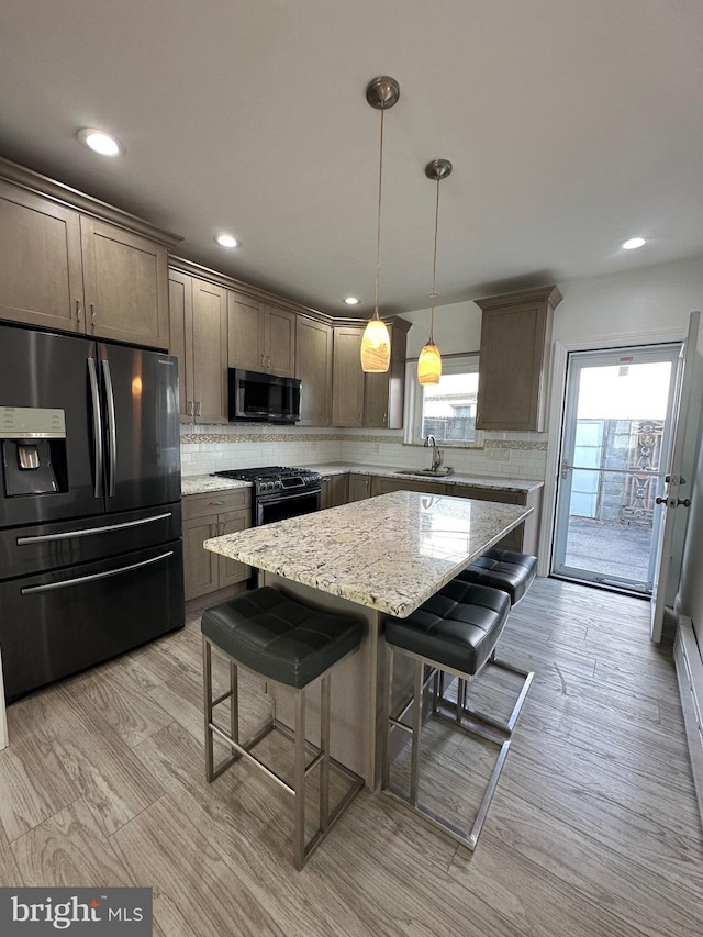 kitchen featuring tasteful backsplash, appliances with stainless steel finishes, a kitchen bar, and a sink