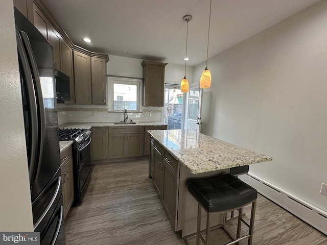 kitchen with backsplash, a baseboard radiator, wood finished floors, black appliances, and a sink