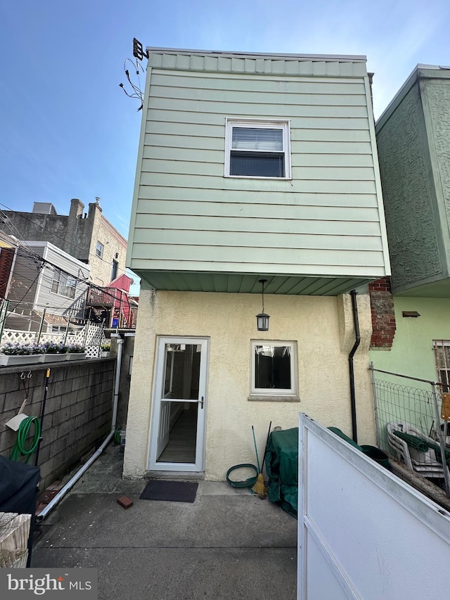 back of property featuring stucco siding and fence