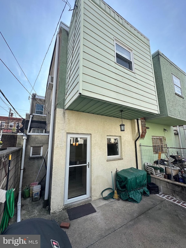 rear view of property featuring stucco siding and fence