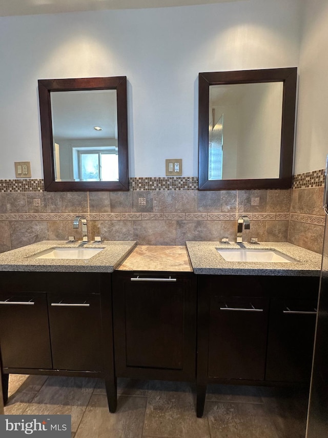 bathroom featuring tile walls, two vanities, and a sink