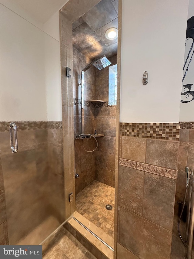 bathroom featuring tile patterned floors, a stall shower, and tile walls