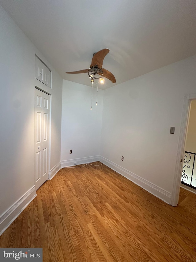 spare room featuring baseboards, light wood-type flooring, and ceiling fan