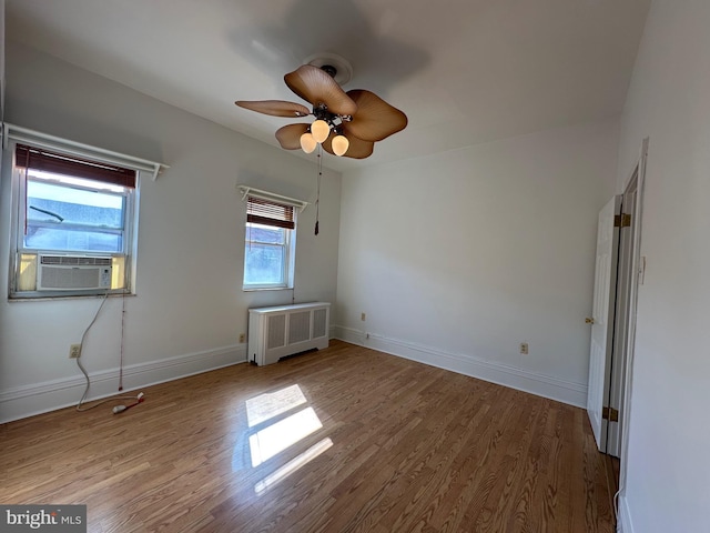 unfurnished bedroom featuring baseboards, radiator, and wood finished floors