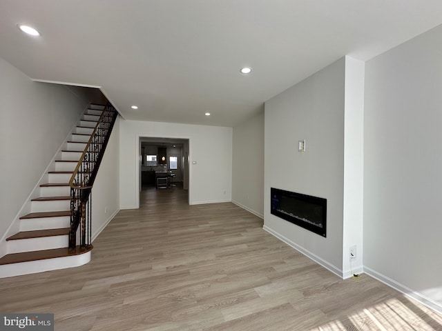 unfurnished living room with recessed lighting, stairway, and light wood-style flooring