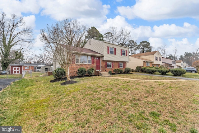 split level home featuring a front yard, a gate, fence, and brick siding