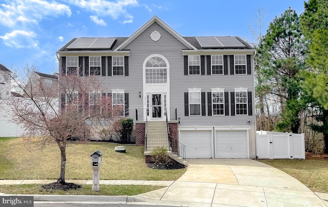 view of front of house featuring roof mounted solar panels, an attached garage, driveway, and a front lawn