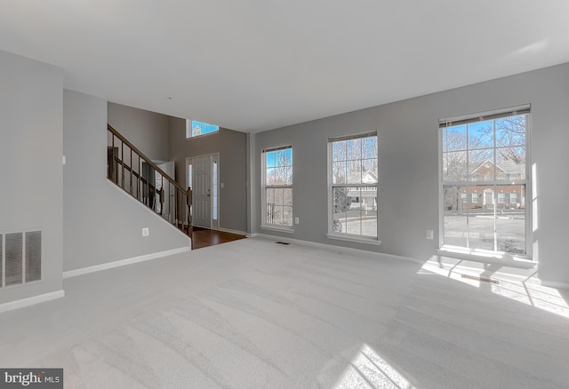 unfurnished living room featuring stairway, carpet flooring, baseboards, and visible vents