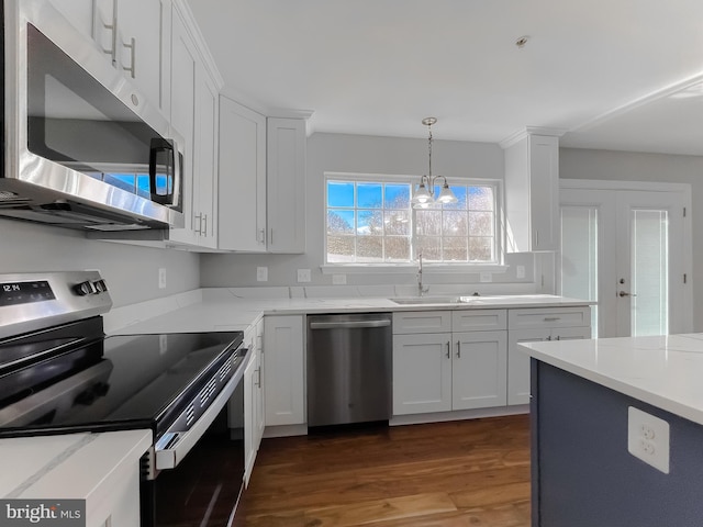 kitchen featuring light stone countertops, white cabinetry, stainless steel appliances, and wood finished floors