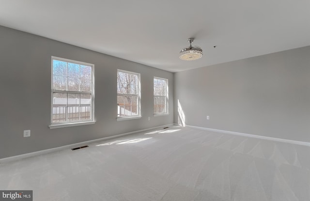 empty room featuring visible vents, carpet floors, and baseboards