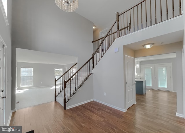 foyer with baseboards, stairs, a towering ceiling, and wood finished floors