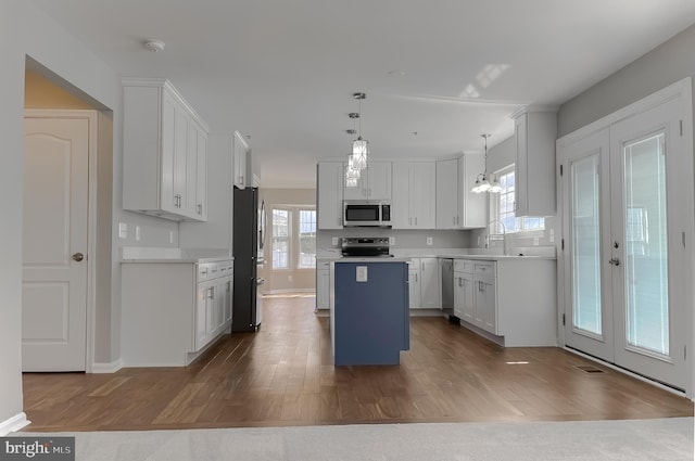 kitchen featuring dark wood finished floors, a kitchen island, white cabinets, and stainless steel appliances