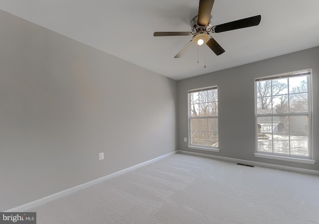 empty room with light carpet, visible vents, ceiling fan, and baseboards