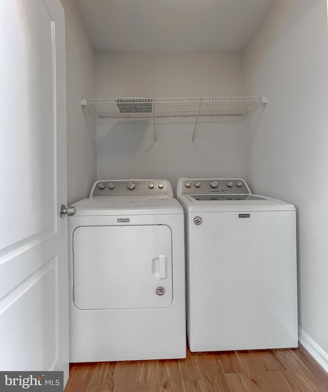 laundry area featuring washer and dryer, laundry area, and wood finished floors